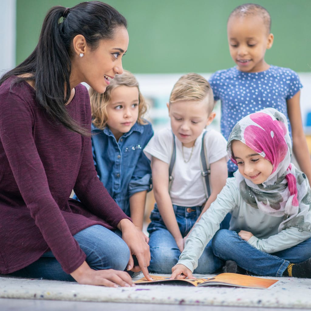 Using Hidden Pictures in Speech Therapy Sessions 1 Image shows a school teacher pointing to a book with a group of young children