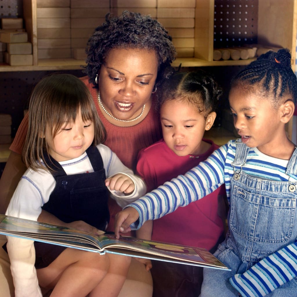 Using Hidden Pictures in Speech Therapy Sessions 2 Image shows a teacher looking at a book with three students. One girl is pointing to the book.